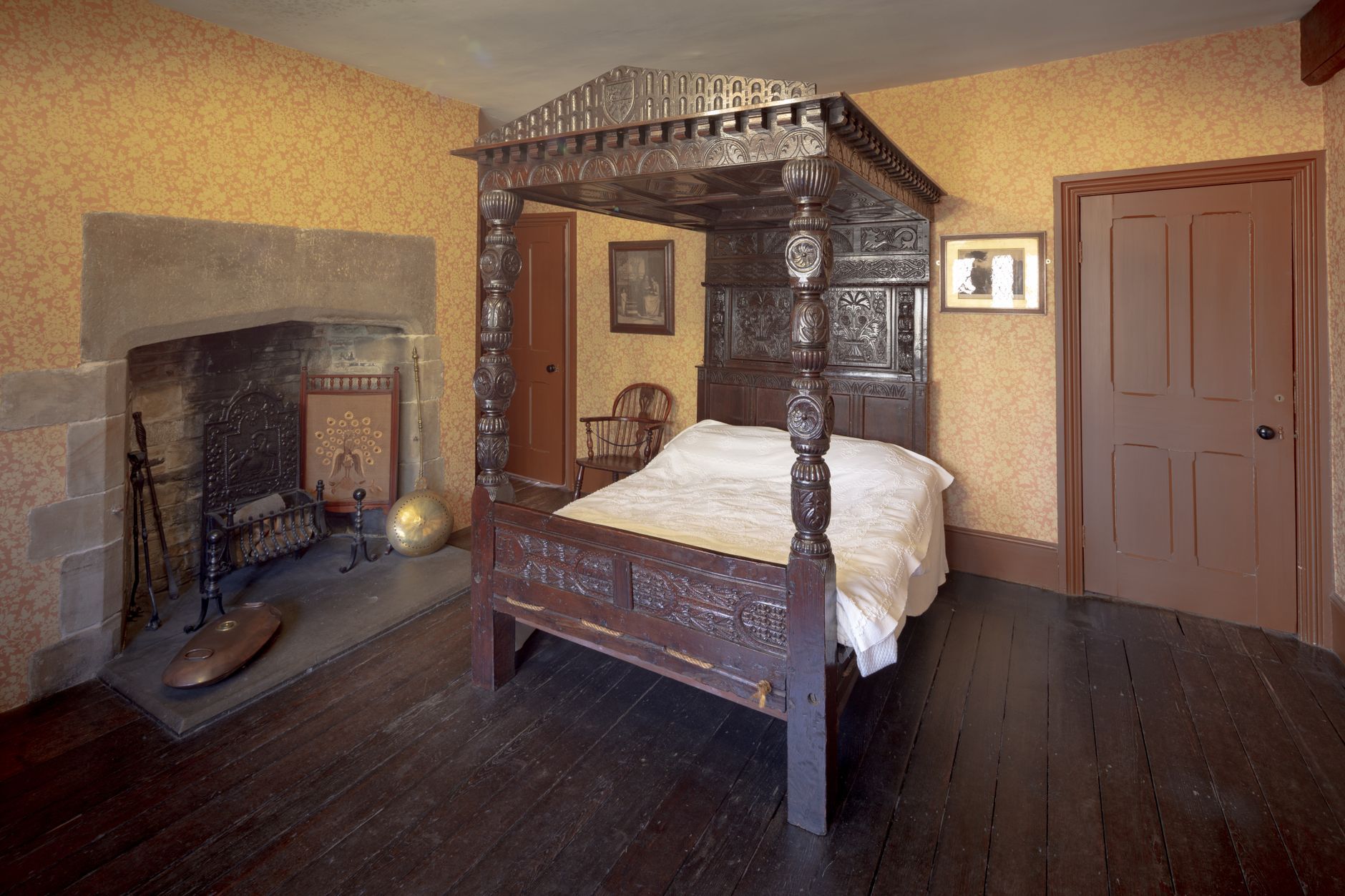 A vintage English bedroom featuring a four-poster bed and ornate fireplace.