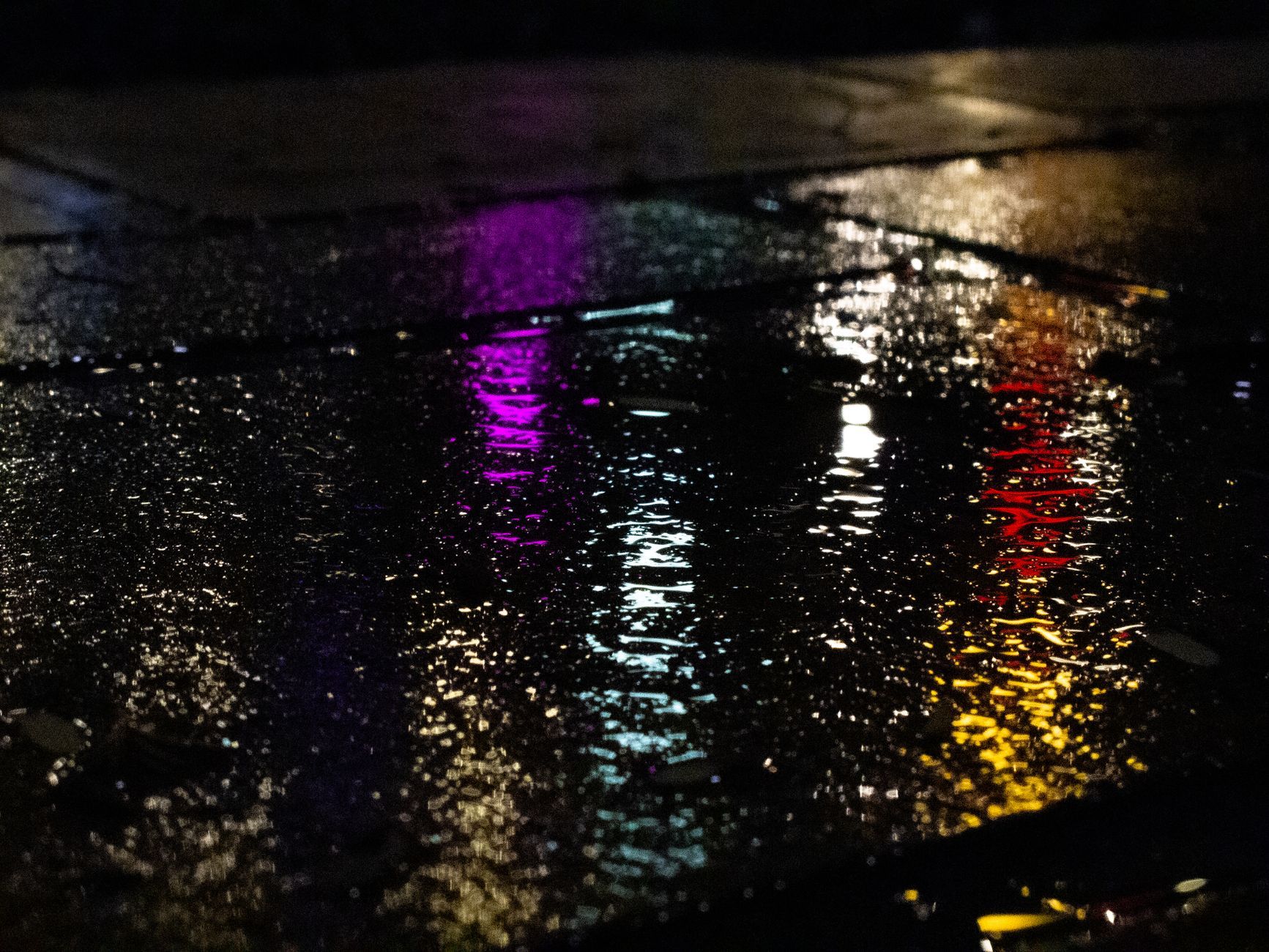 Colorful neon reflections on wet pavement capture urban nightlife ambiance in Taiwan.